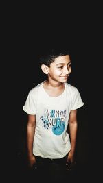 Girl looking away while standing against black background