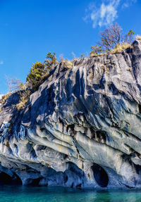 Low angle view of rock formation in sea against blue sky