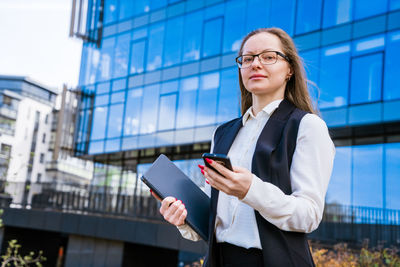 Happy woman in trendy glasses and business suit is focused on getting