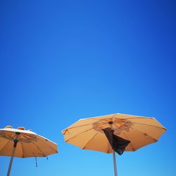 Low angle view of umbrella against clear blue sky