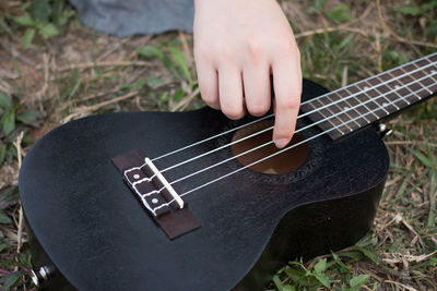 Cropped image of person playing guitar on field