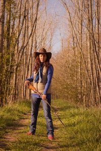 Portrait of woman with rifle standing in forest