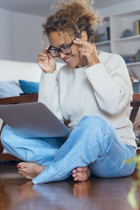 Young woman using mobile phone while sitting at home