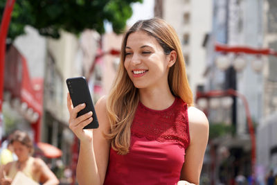 Portrait of attractive smiling woman walking in sao paulo city texting on mobile phone