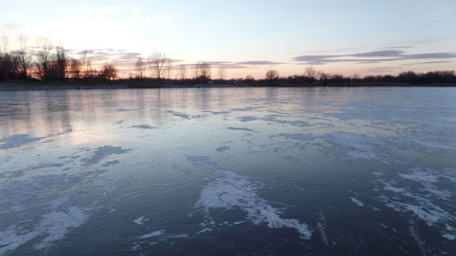 Scenic view of frozen lake against sky during sunset