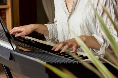 Female musician playing the digital piano or electronic keyboard at home. music education. 