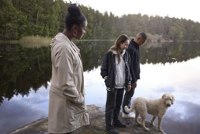 Friends with dog standing at lake