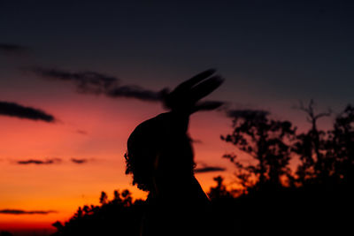 Silhouette woman against orange sky