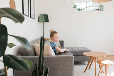 Young girl sat on the couch playing the guitar, at home