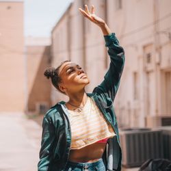 Young woman with arm raised in city