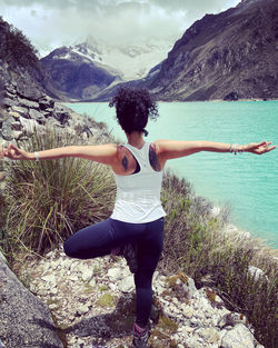 Full length of young woman doing yoga on mountain