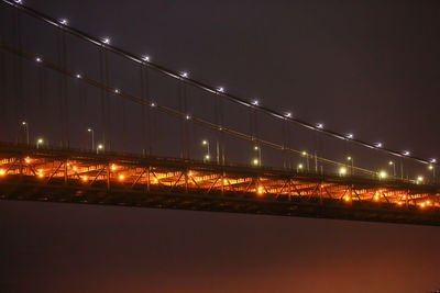 Illuminated suspension bridge against sky at night