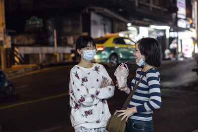 Young women in face masks talking in street