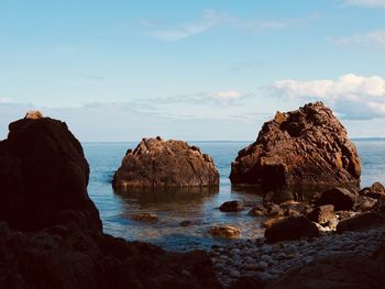 Rocks on sea shore against sky