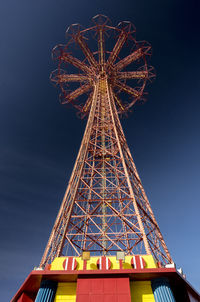 Low angle view of illuminated ferris wheel against blue sky