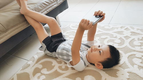High angle view of cute boy holding mobile phone at home