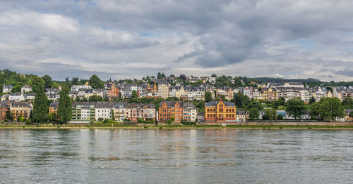 Buildings by river against sky in town