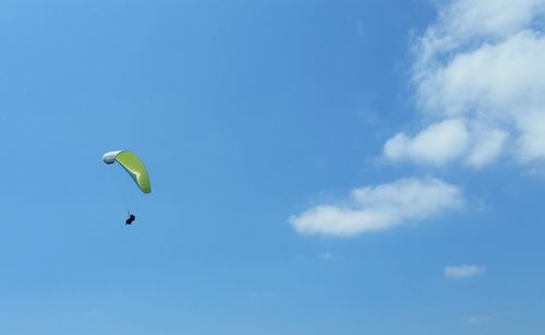 Low angle view of person paragliding against blue sky