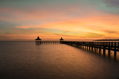 Silhouette pier over sea against sky during sunset
