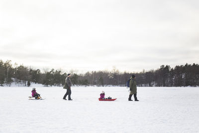 People on snow covered landscape against sky