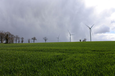 Windmills on field against sky