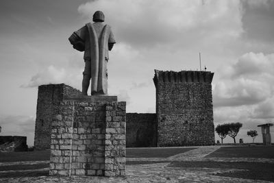 Statue in front of built structure against sky