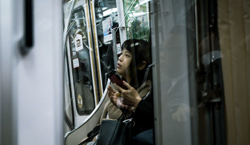 Full length of woman looking through train window