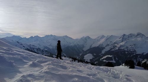 Man skiing on snowcapped mountain against sky