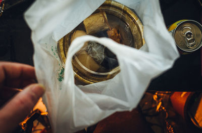 Cropped hand with food in plastic bag on table