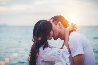 Young couple kissing against sea