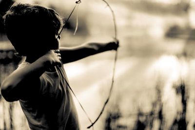 Side view of boy with bow and arrow