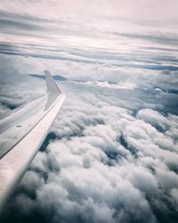 View of airplane wing over clouds