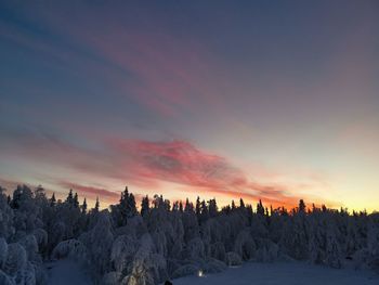 Snow covered landscape against sky during sunset