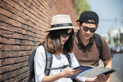 Man discussing map with woman while standing in city