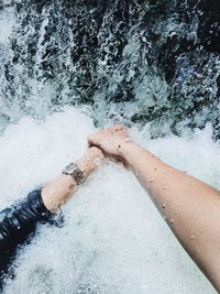 Cropped mage of couple holding hands in water