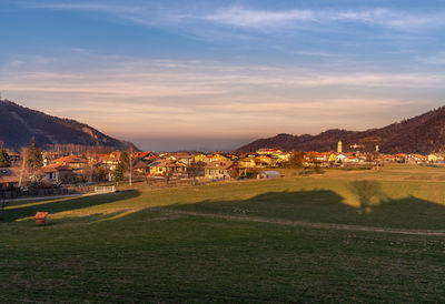 Scenic view of field by city against sky