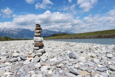 Stack of pebbles on shore against sky