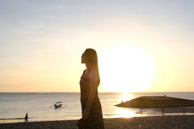 Woman on beach against sky during sunset