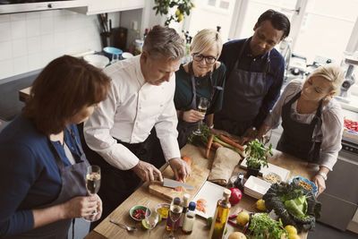 Concentrated students looking at chef cutting salmon in kitchen