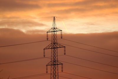 Low angle view of silhouette electricity pylon against romantic sky