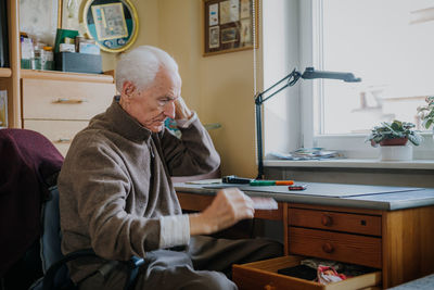 Side view of senior man holding comb at home