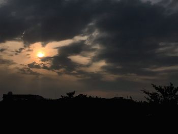 Silhouette trees against dramatic sky during sunset