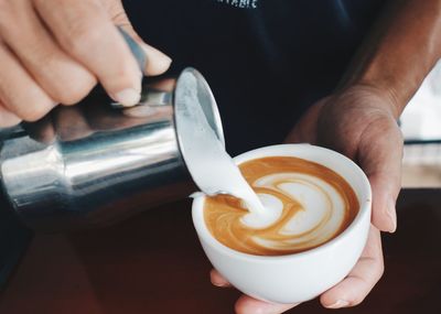 Close-up of hand holding coffee on table