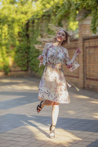 Portrait of smiling woman dancing on footpath in park