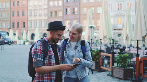 Young man using phone while standing on street in city