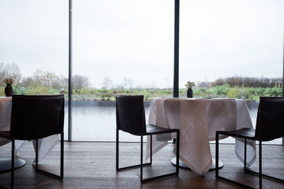 Empty chairs and table arranged by window in restaurant