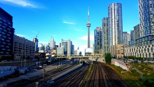 Railroad tracks by cn tower in city against sky