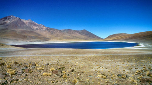 Scenic view of land and mountains against clear blue sky