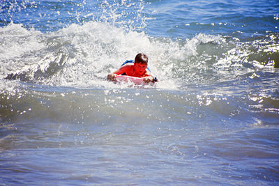 Boy surfboarding in sea