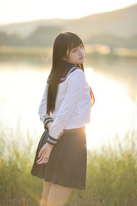 Young woman standing against trees